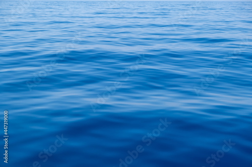 Sea water surface calm with small ripples. Still ocean, deep blue color background,.