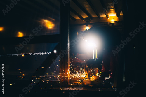 A man is sawing metal pipes on a plunge-cut miter saw. Sparks is flying from under the disc. The working process. DIY construction. Hobby. Safety precautions for using power tools. Protection means photo
