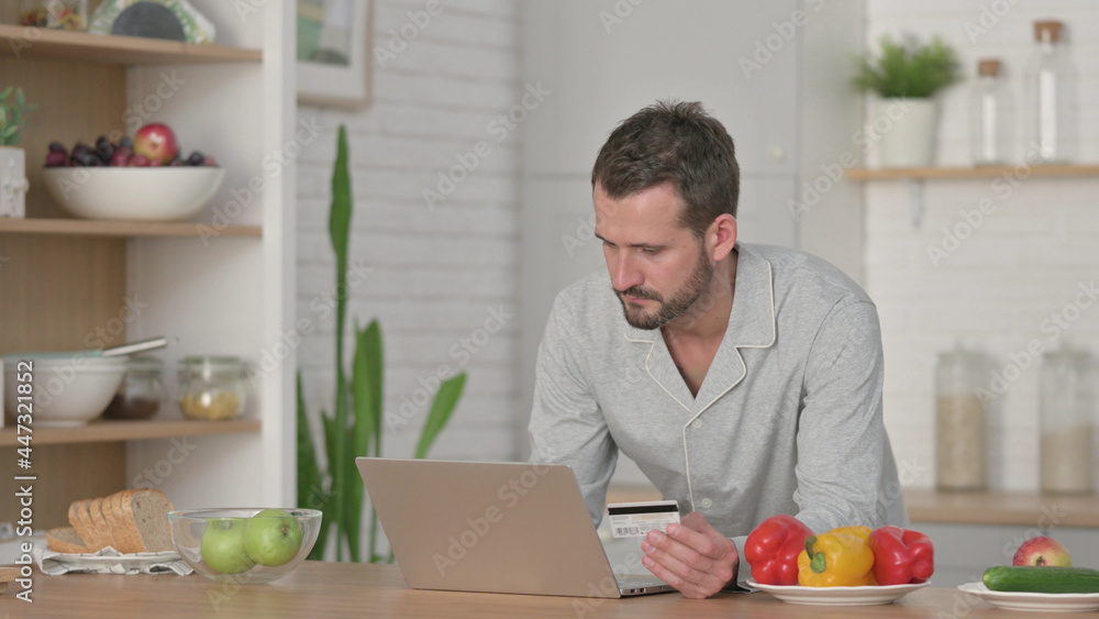 Man Doing Online Shopping on Laptop in Kitchen Man Doing Online Shopping on Laptop in Kitchen