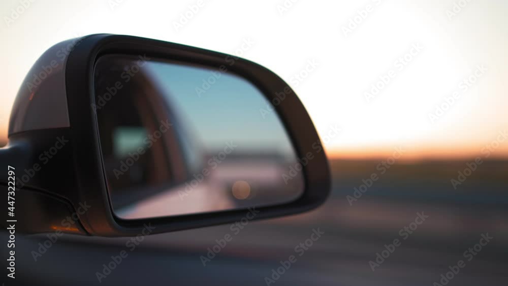View in the side mirror of a car that is driving fast on the highway in the sunset light. Travel and trip concept. View in the side mirror of a car that is driving fast on the highway in the sunset light. Travel and trip concept.