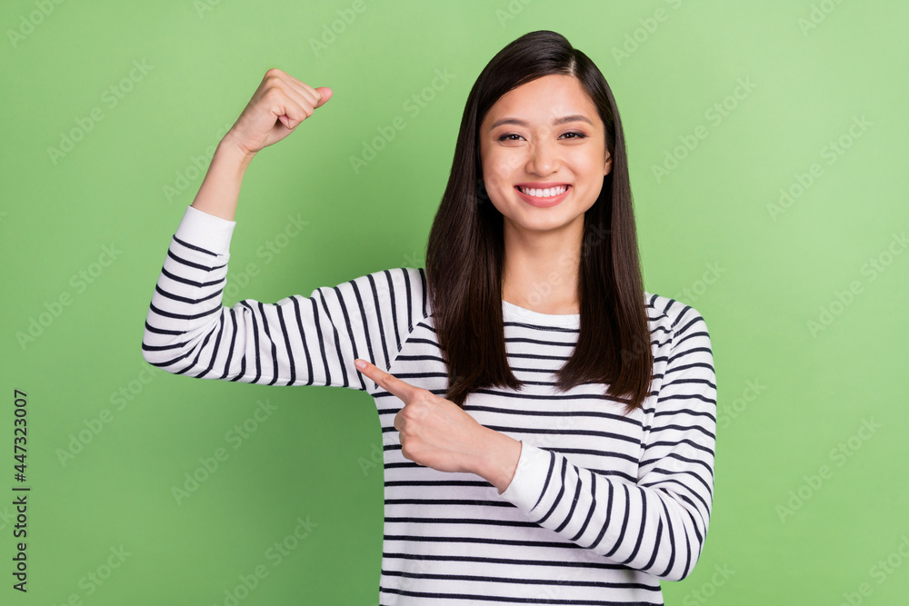 Portrait of attractive confident cheerful girl demonstrating arm muscles isolated over green color background Portrait of attractive confident cheerful girl demonstrating arm muscles isolated over green color background