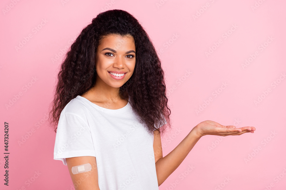 Photo of sweet cute dark skin woman dressed white t-shirt vaccination done holding arm empty space isolated pink color background Photo of sweet cute dark skin woman dressed white t-shirt vaccination done holding arm empty space isolated pink color background