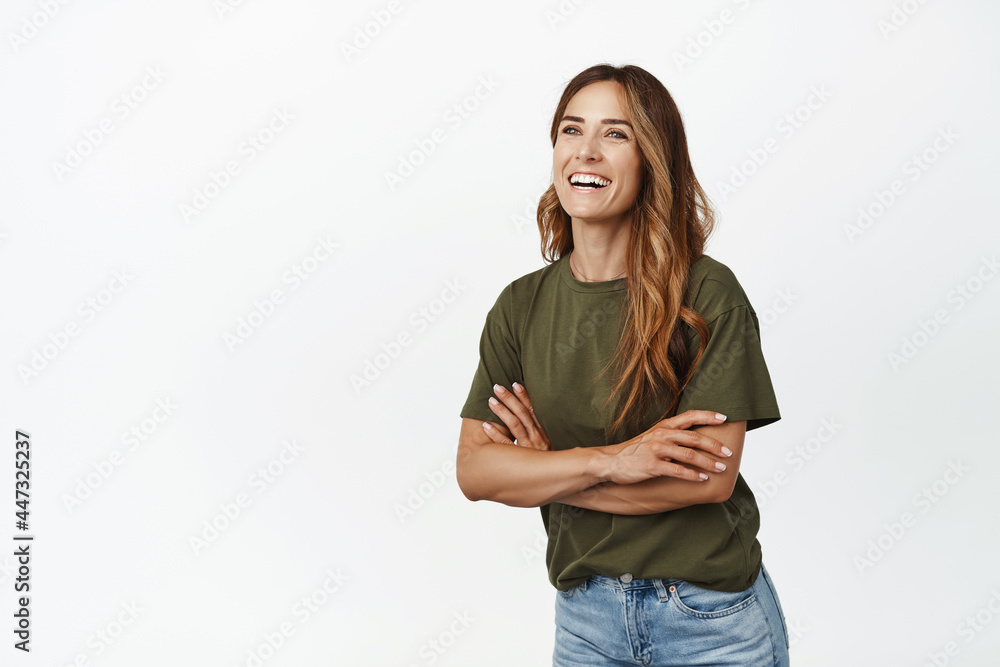 Cheerful caucasian woman cross arms on chest, laughing and smiling white teeth, looking aside left at promo text, posing with cheerful face expression, studio background Cheerful caucasian woman cross arms on chest, laughing and smiling white teeth, looking aside left at promo text, posing with cheerful face expression, studio background