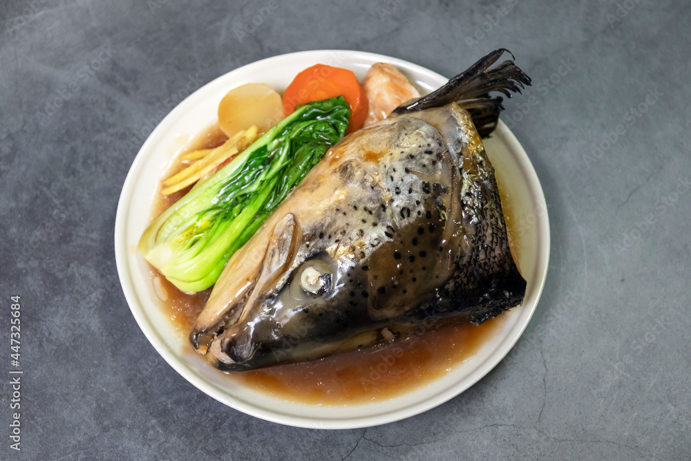 Salmon Kabutoni; Salmon head soup in soy sauce with bok choy, carrot, radish and ginger. Top view on black table background. Salmon Kabutoni; Salmon head soup in soy sauce with bok choy, carrot, radish and ginger. Top view on black table background.