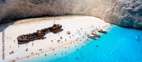 The beautiful Navagio shipwreck beach with turquoise sea and tourists enjoying the sea, Zakynthos island, Greece photo