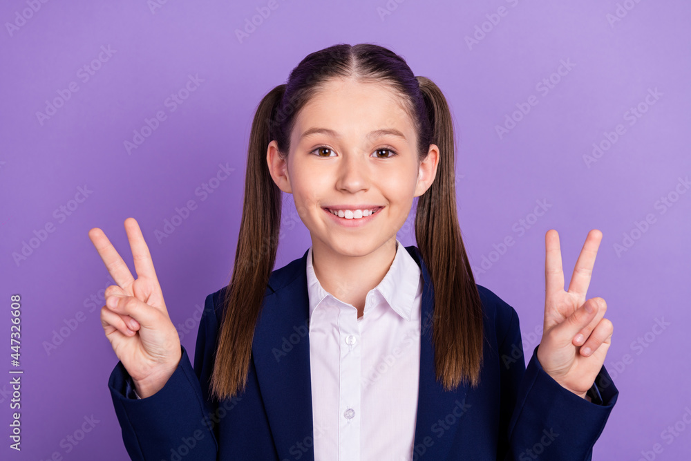 Photo of funny adorable school girl wear blue uniform showing v-signs smiling isolated purple color background