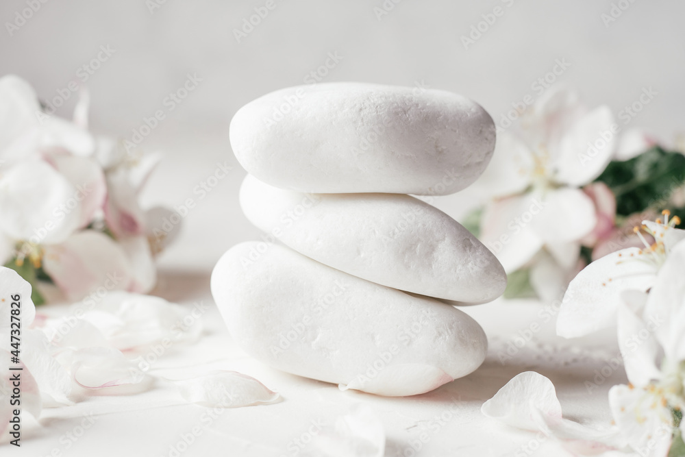 Stack of white pebble stones on light plaster surface, with apple flowers Stack of white pebble stones on light plaster surface, with apple flowers