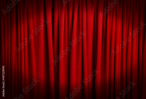 Spotlight illuminating closed red stage curtains. Start of performance