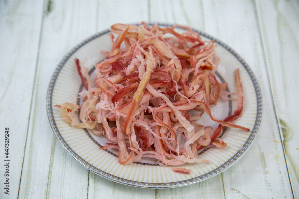 Squid shavings (Lat. Teuthida) on a round plate with a wooden table background. Food is a delicacy snack for beer. Squid shavings (Lat. Teuthida) on a round plate with a wooden table background. Food is a delicacy snack for beer.