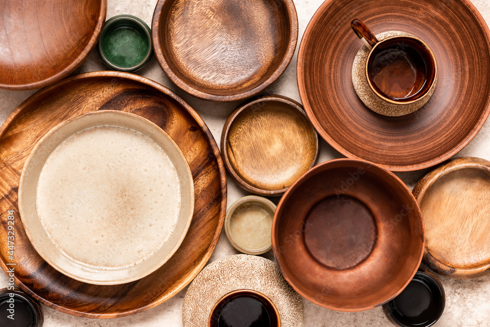 Many different ceramic and wooden plates and bowls on a beige background top view. Flat lay. Background from empty plates and bowls. Various empty dishes. Many different ceramic and wooden plates and bowls on a beige background top view. Flat lay. Background from empty plates and bowls. Various empty dishes.