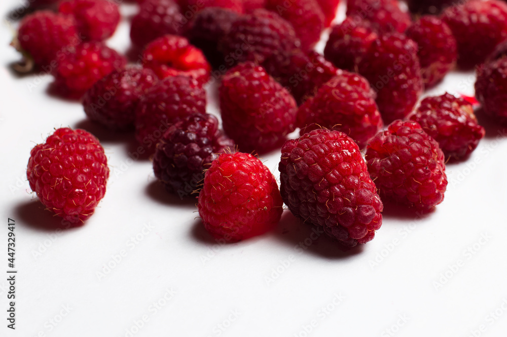 Close-up studio photo of fresh raspberries spread on the white background. Close-up studio photo of fresh raspberries spread on the white background.