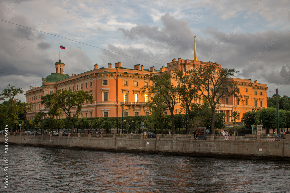 view of the orange Mikhailovsky Castle on the Fontanka River embankment on a summer evening at sunset and a space for copying in Saint-Petersburg