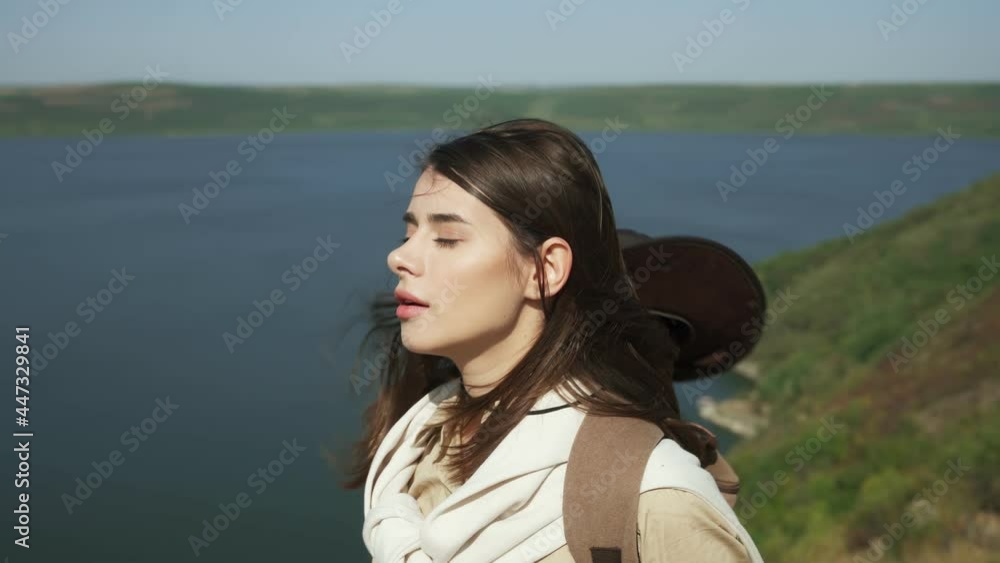 Attractive woman with brown hair breathing deeply of fresh air at national ukrainian park. Female hiker with backpack standing high near Dniester river. Attractive woman with brown hair breathing deeply of fresh air at national ukrainian park. Female hiker with backpack standing high near Dniester river.