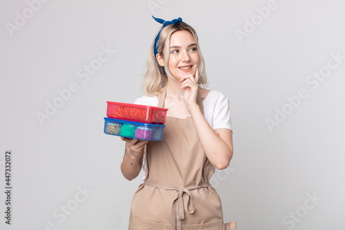 young pretty albino woman smiling happily and daydreaming or doubting holding food tupperwares photo