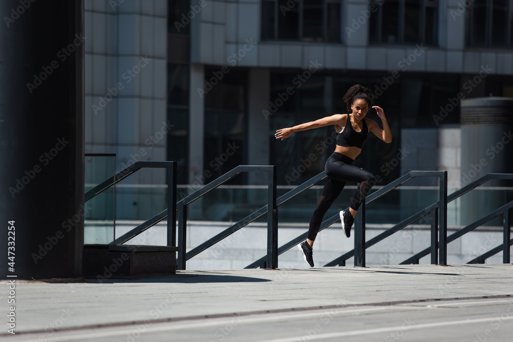 African american runner training near railing on urban street