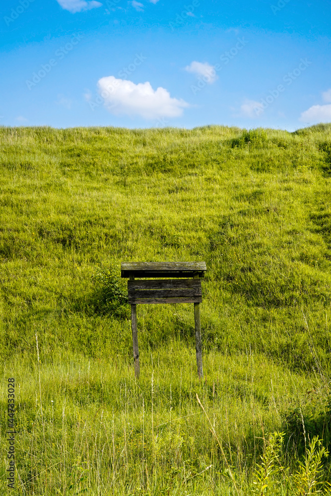 rustic wooden signboard and green hill, blue sky with clouds rustic wooden signboard and green hill, blue sky with clouds