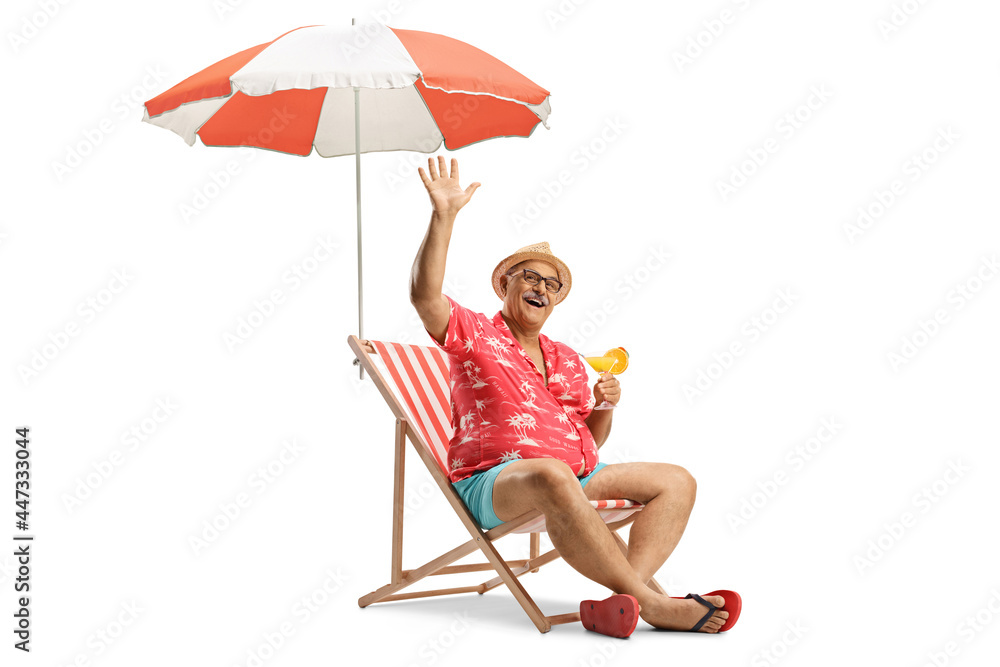 Mature male tourist sitting with a cocktail under umbrella and waving