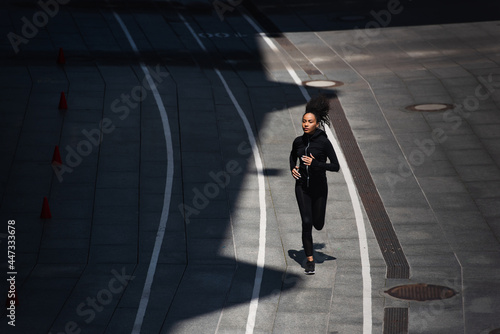 High angle view of young african american sportswoman running on track on urban street