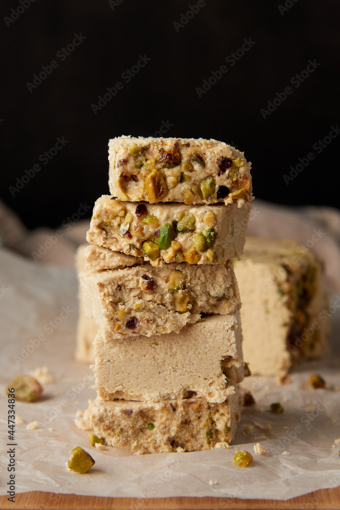 Organic halva with pistachios on a wooden surface. Traditional middle eastern sweets. Jewish, turkish, arabic oriental national dessert. Turkish delight concept. Natural vegan product. Copy space.
