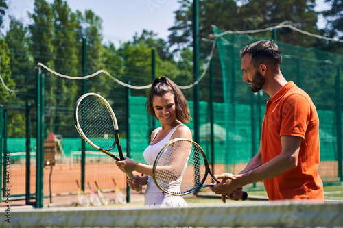 Instructor showing a proper tennis grip technique to his client © Viacheslav Yakobchuk
