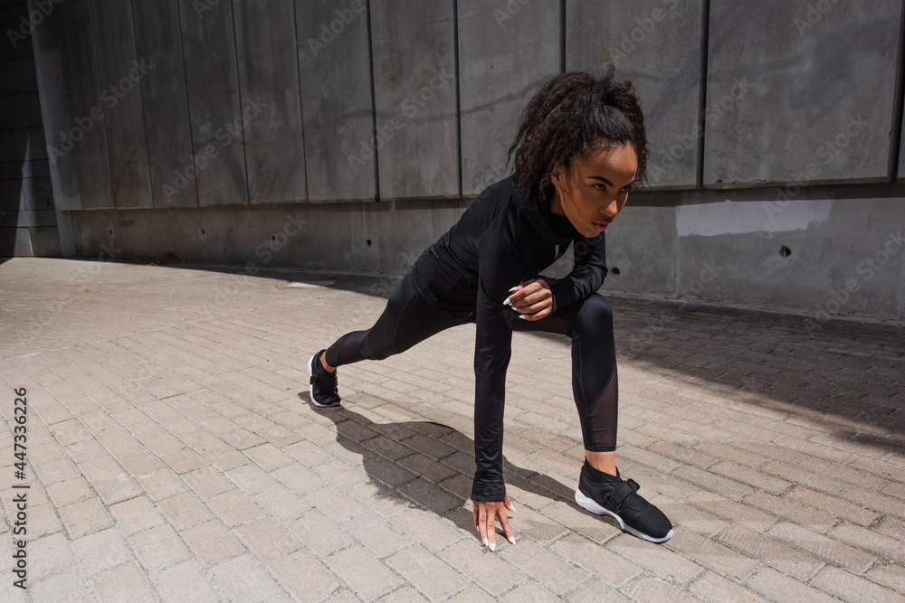 African american runner standing in starting pose on urban street African american runner standing in starting pose on urban street