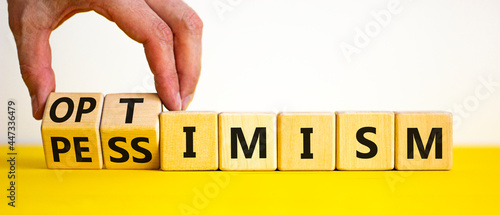 Pessimism or optimism symbol. Businessman turns cubes and changes the word 'pessimism' to 'optimism'. Beautiful yellow table, white background. Business, optimism or pessimism concept. Copy space. photo