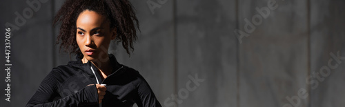 Принти на полотні Young african american sportswoman zipping sports jacket outdoors, banner