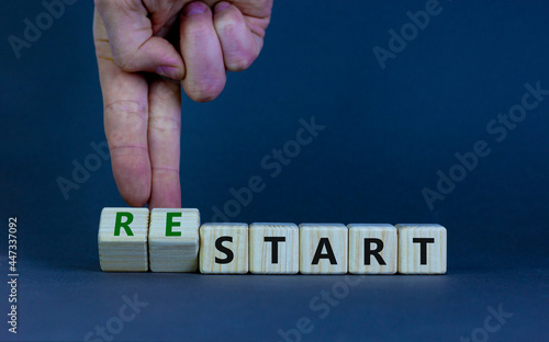 Start or restart symbol. Businessman turns wooden cubes and changes the word 'start' to 'restart'. Beautiful grey table, grey background. Business, start or restart concept. Copy space.