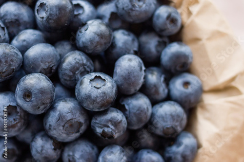 A lot of beautiful juicy fresh summer blueberries in a brown bag on a light background