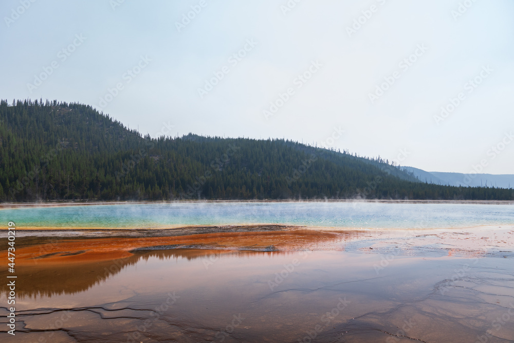 Yellowstone National Park steaming Prismatic Opal Pool reflecting the background forested mountain Yellowstone National Park steaming Prismatic Opal Pool reflecting the background forested mountain