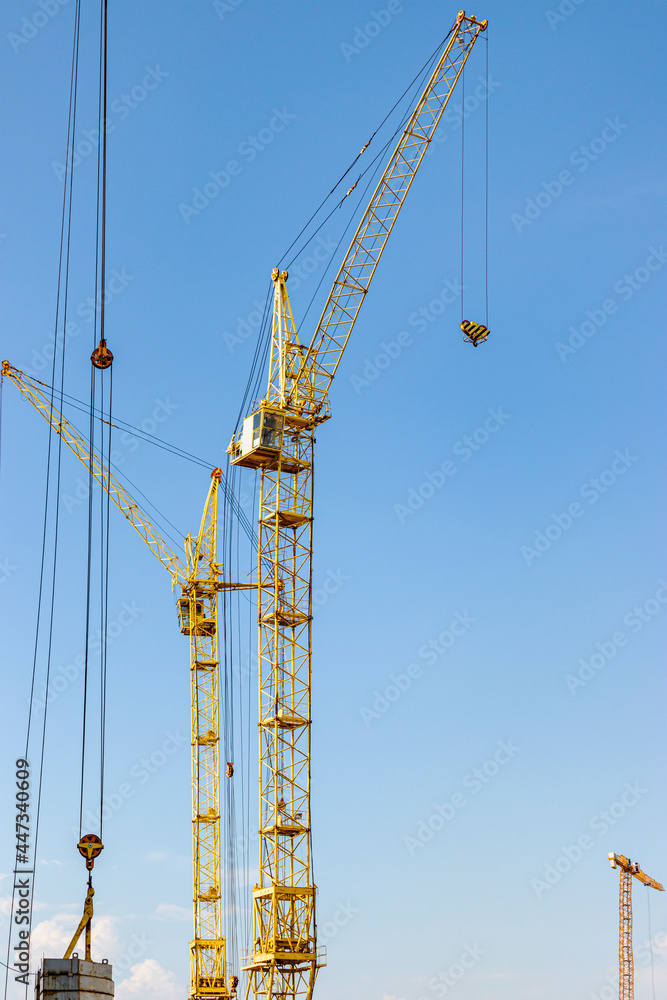 The work of tower cranes against the background of the sunset sky. Modern housing construction. Industrial engineering. Construction of mortgage housing.