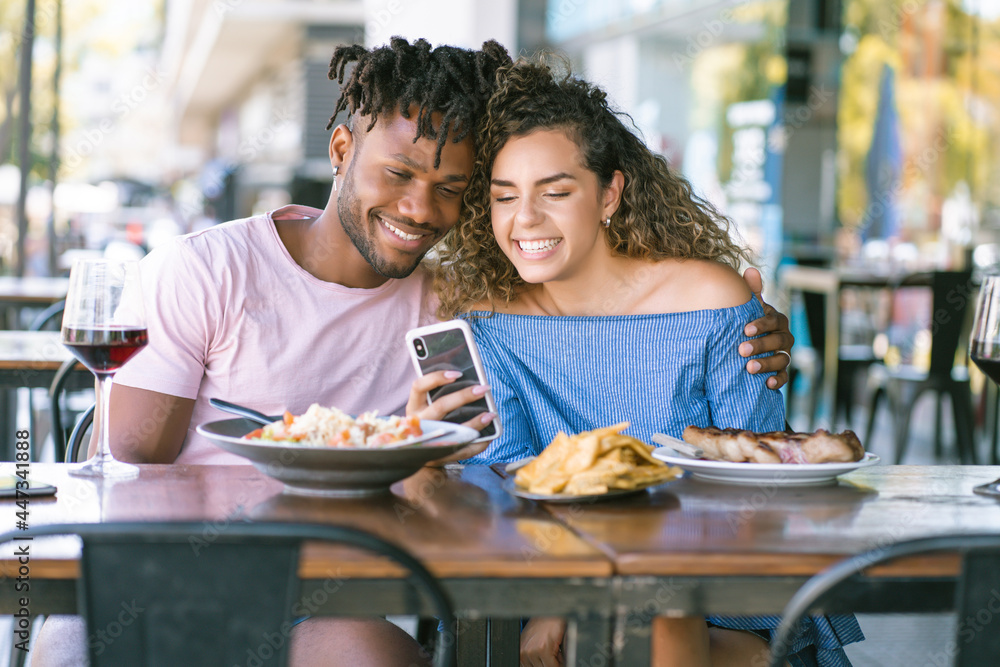 Couple using a mobile phone at a restaurant. Couple using a mobile phone at a restaurant.