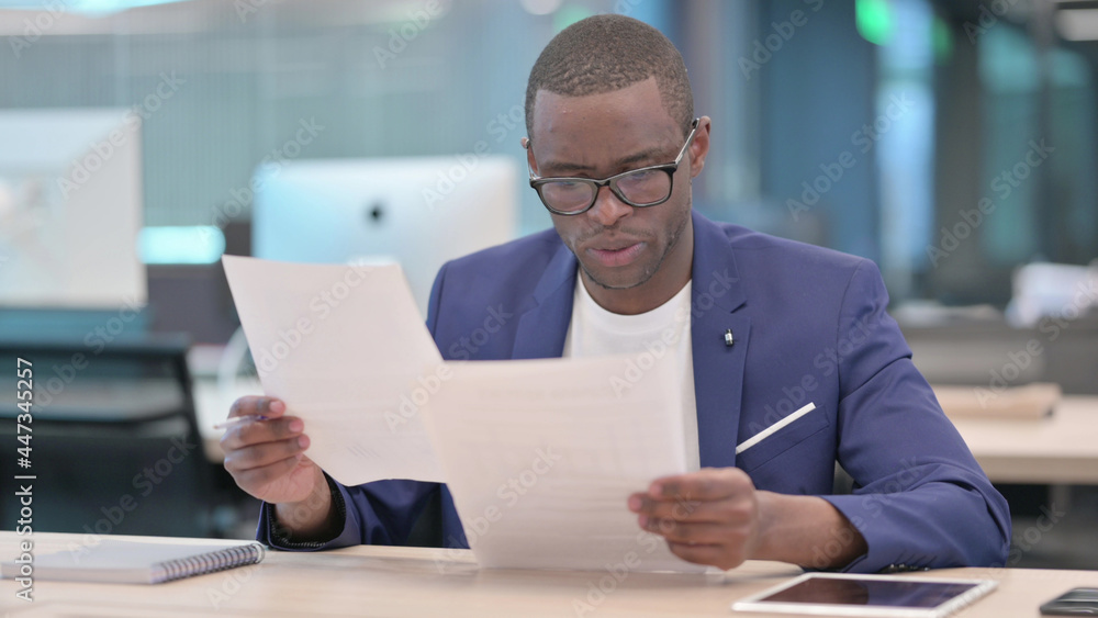 Pensive Young African Businessman Reading Docusments, Paperwork