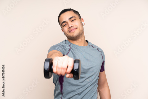 Asian sport man isolated on beige background making weightlifting