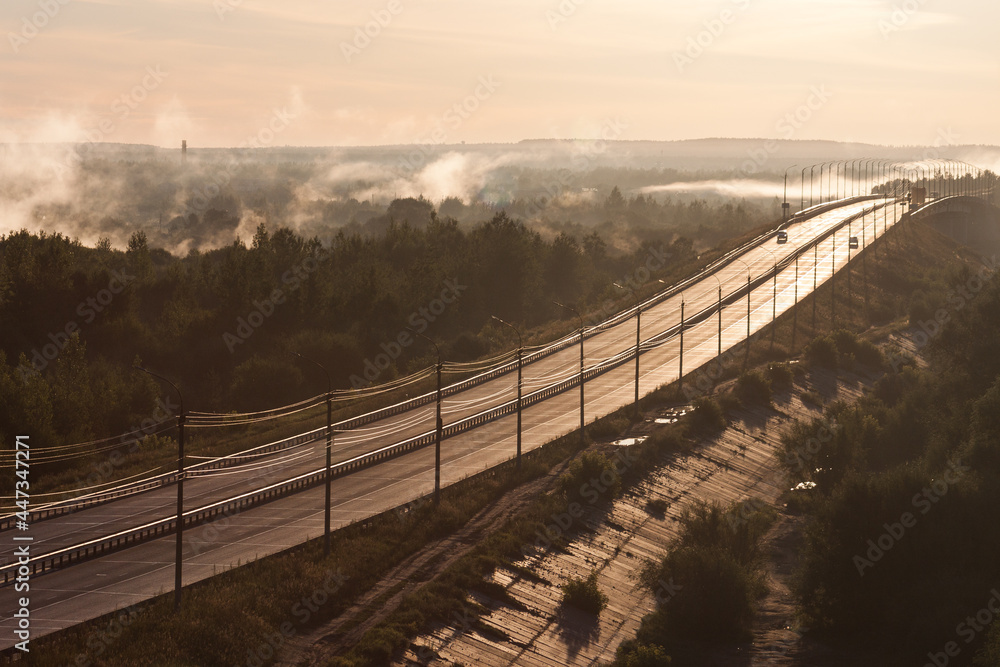 Sunrise and fog over the highway and the bridge over the river.