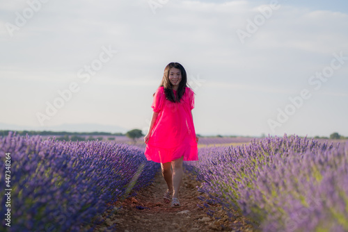young Asian woman outdoors at lavender flowers field - happy and beautiful Chinese girl in sweet Summer magenta dress enjoying holidays relaxed on purple floral meadow © TheVisualsYouNeed