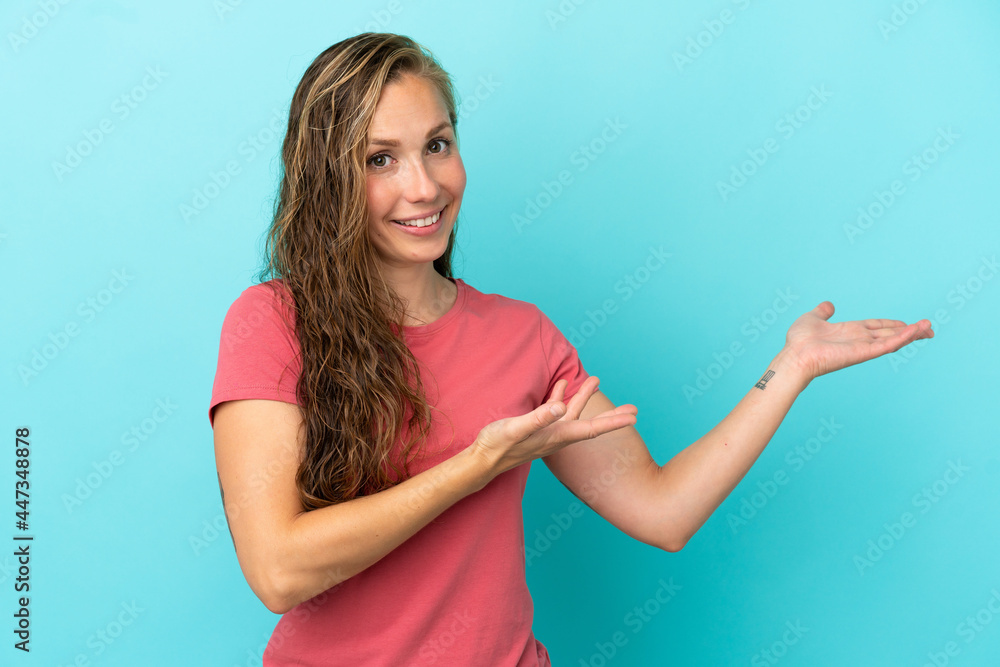 Young caucasian woman isolated on blue background extending hands to the side for inviting to come Young caucasian woman isolated on blue background extending hands to the side for inviting to come