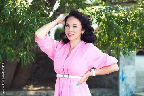 Young woman in pnk linen dress outdoor portrait, smiling face, looking at camera photo