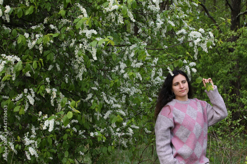 Portrait of a brunette woman with long hair with a flowering tree in a rural park in nature in spring Portrait of a brunette woman with long hair with a flowering tree in a rural park in nature in spring