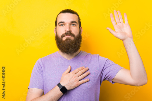 фотографія Photo of a young bearded man swearing solemnly while looking at the camera