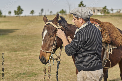 gaucho argentino , colocando riendas al caballo photo