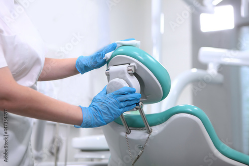 Dental assistant wipes the dental chair. Disinfection of dental equipment. Health care concept. Unrecognizable person.