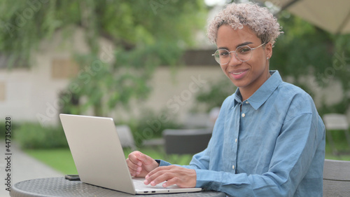 African Woman with Laptop Shaking Head as Yes Sign in Outdoor Cafe