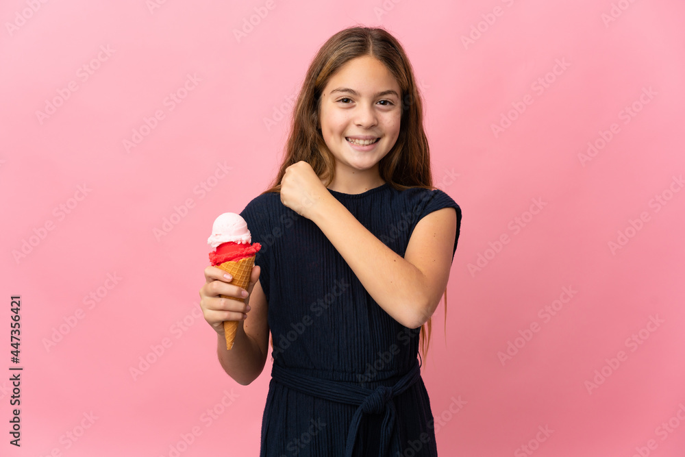 Child with a cornet ice cream over isolated pink background celebrating a victory Child with a cornet ice cream over isolated pink background celebrating a victory