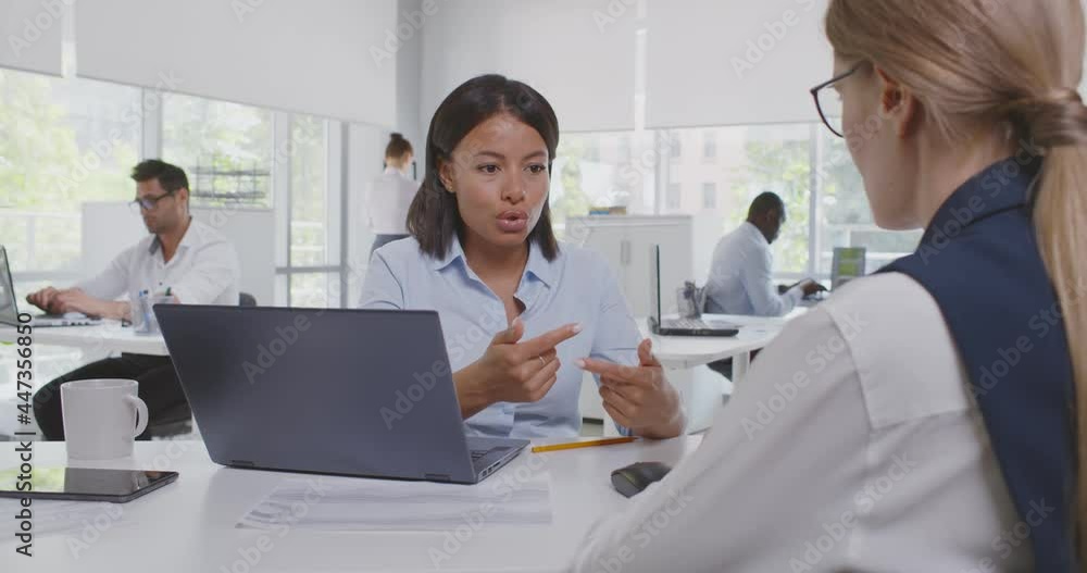 View over shoulder of caucasian female applicant having job interview of african woman hr manager View over shoulder of caucasian female applicant having job interview of african woman hr manager