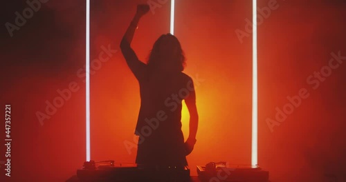 Hot dj rave. Silhouette of dancing deejay young guy rocking party up in red light in smoke in nightclub photo