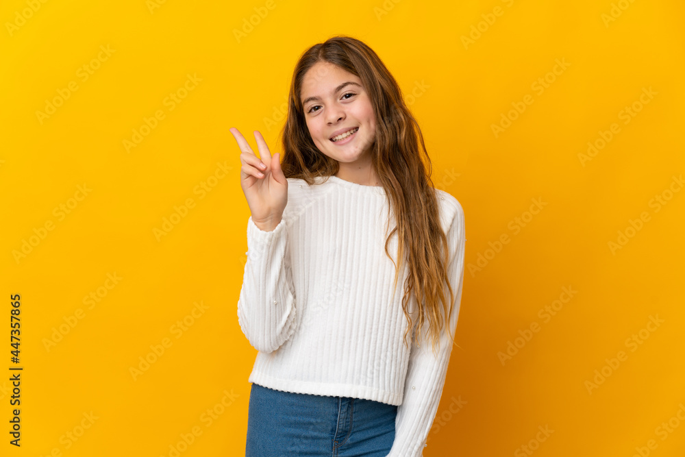 Child over isolated yellow background smiling and showing victory sign Child over isolated yellow background smiling and showing victory sign