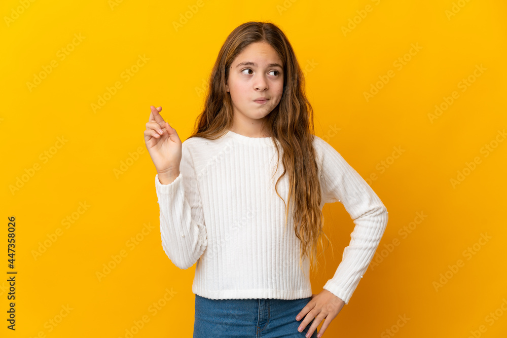 Child over isolated yellow background with fingers crossing and wishing the best Child over isolated yellow background with fingers crossing and wishing the best