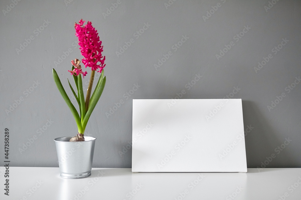 Blank canvas and flower on white table on gray wall background Blank canvas and flower on white table on gray wall background