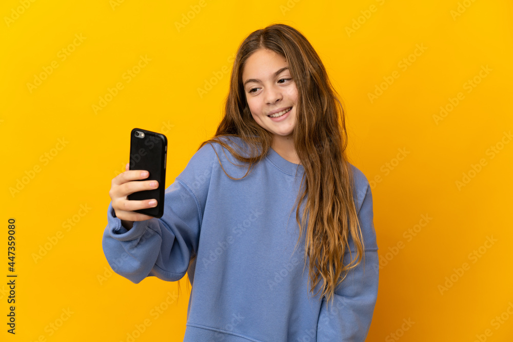 Fototapeta premium Child over isolated yellow background making a selfie